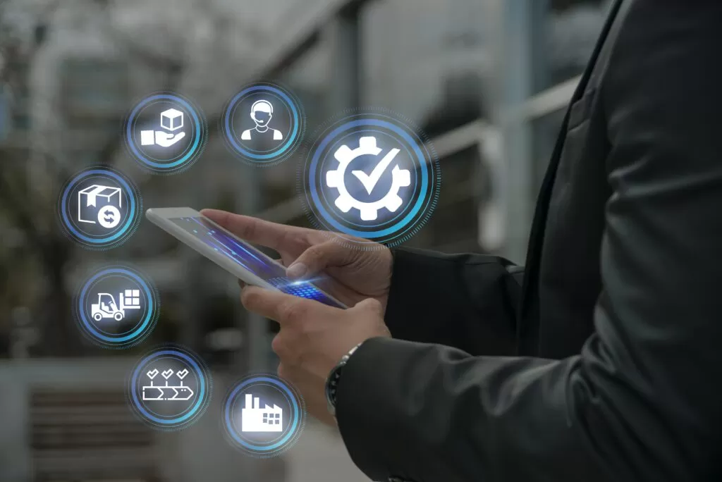 Tablet exibindo visualmente ícones representando etapas da cadeia logística (armazenagem, transporte, produção, entrega, qualidade, custos, pessoas), destacando a importância de monitorar KPIs em cada área.