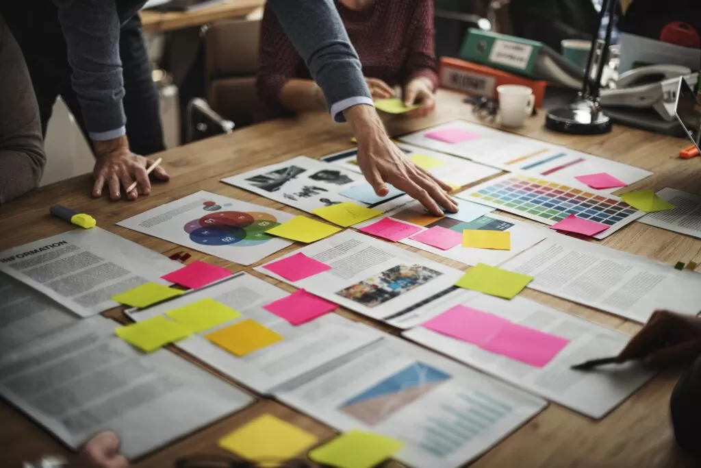 Grupo de pessoas colaborando em documentos de planejamento, representando a possível contribuição de soluções de Inteligência Artificial para o planejamento estratégico integrado.
