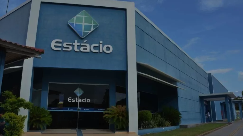 Fachada de uma unidade da Estácio (pertencente ao grupo Yduqs) com a logomarca da instituição, representando o contexto de planejamento acadêmico e a possível aplicação de Inteligência Artificial (IA) no setor educacional da Yduqs. Ilustração para artigo sobre como a IA pode ser utilizada para otimizar currículos, personalizar o aprendizado e melhorar a gestão acadêmica na Yduqs.