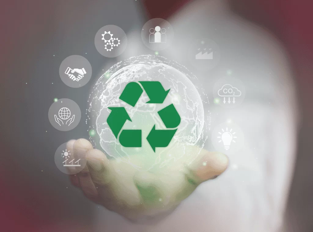 Mão segurando globo com ícone de reciclagem e símbolos de sustentabilidade (painéis solares, turbinas eólicas, carros elétricos), ilustrando a integração de ESG na logística para operações mais sustentáveis.