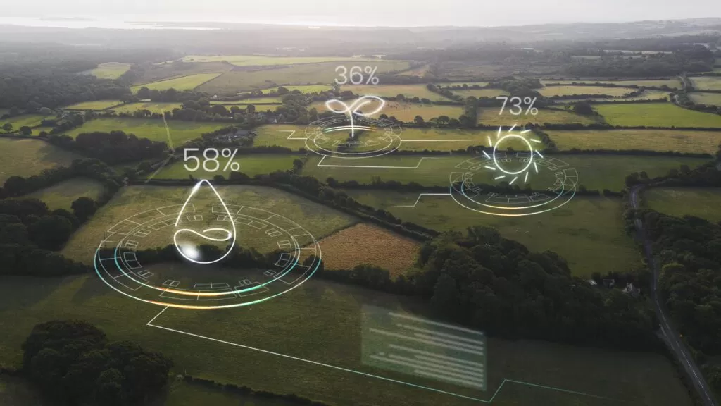 Visão aérea de campos agrícolas com sobreposição de gráficos digitais mostrando dados de sustentabilidade. Ícones representam água, crescimento e energia solar, destacando como a tecnologia de dados otimiza operações logísticas sustentáveis.