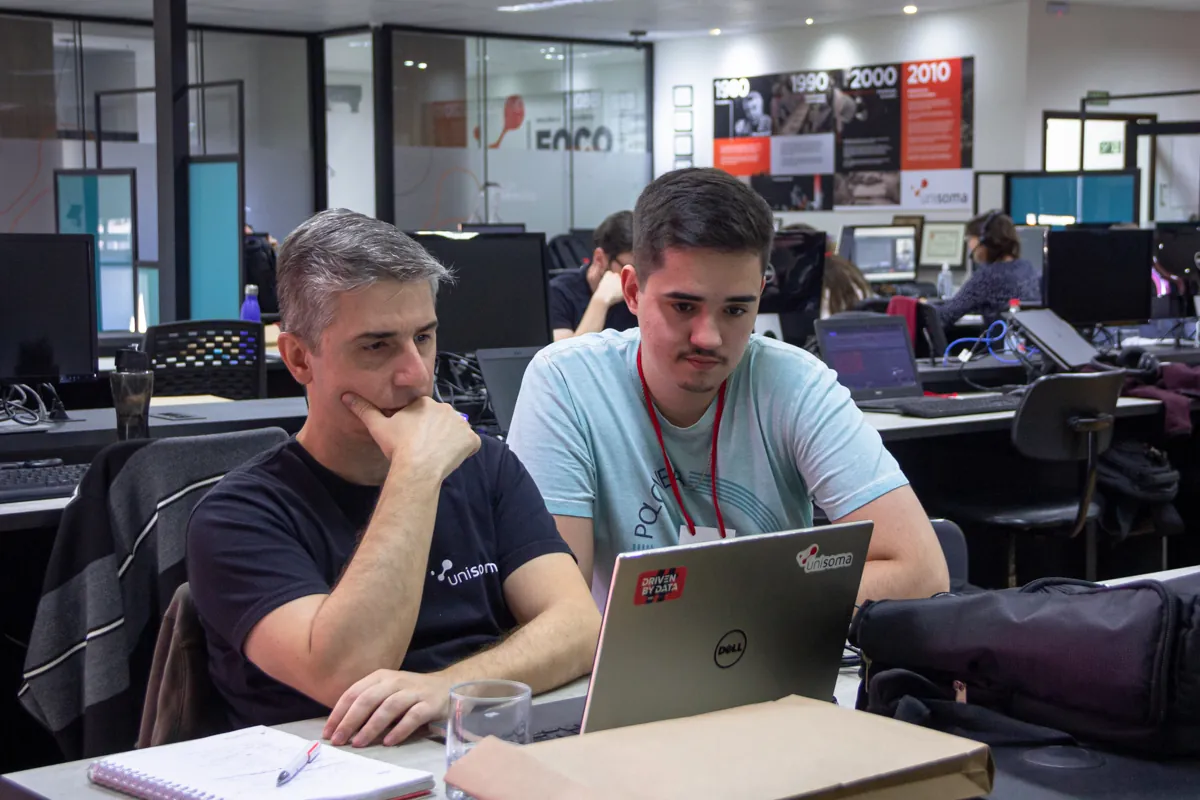 Dois profissionais da UniSoma analisando dados juntos em um laptop