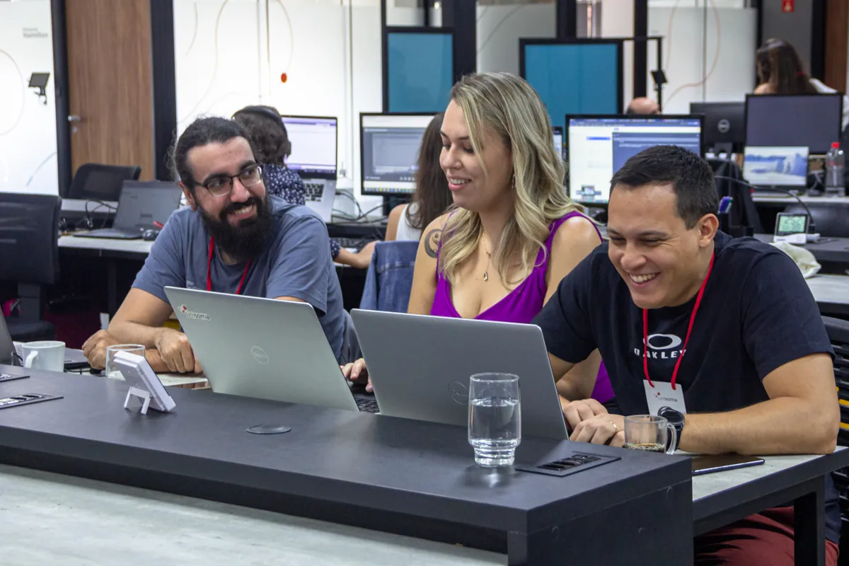 Profissionais da UniSoma sorrindo durante trabalho em equipe no escritório